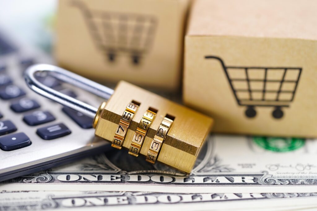 Golden digital security lock and shopping cart on US dollar banknotes, representing secure online financial transactions in the real estate sector.