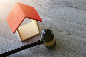 Toy house and judge gavel on wooden table, symbolizing the protection of homebuyer's rights by title insurance.