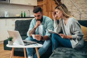 Young worried couple using a laptop, symbolizing the importance of securing owner’s title insurance for homebuyers’ peace of mind.