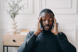 Frustrated man holding head in hands after experiencing unexpected delays in real estate closing due to title issues